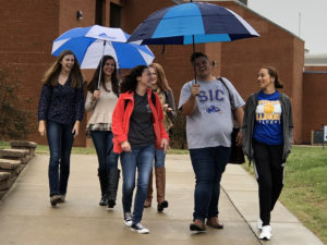 SIC students walking on campus holding umbrellas