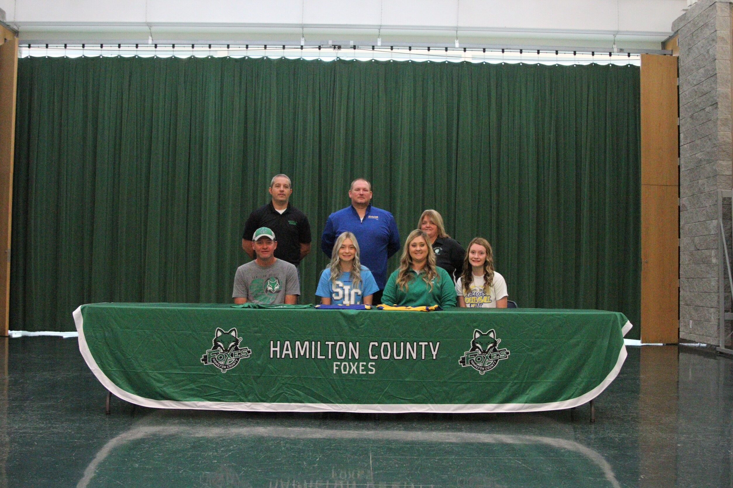 Chayli Phelps sits at table with family and coaches after signing letter of intent for SIC Volleyball