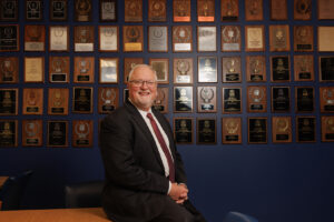 Dr Jonah Rice With Forensic Falcons Awards Wall